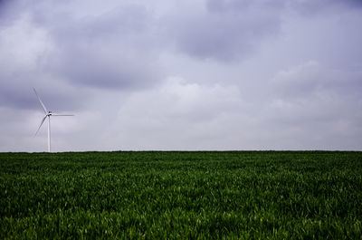 Windmills on field against sky