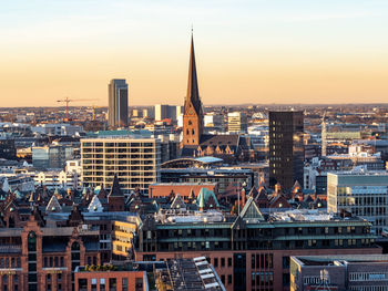 Modern buildings in city against sky during sunset