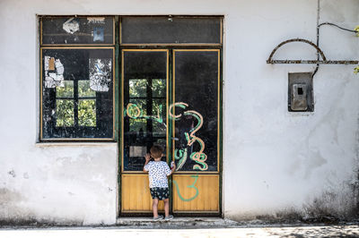 Woman standing by window of building