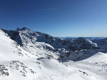 Scenic view of snowcapped mountains against blue sky