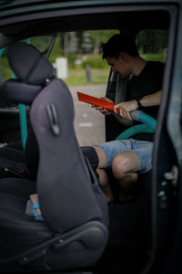 Caucasian man vacuuming a car at a gas station.