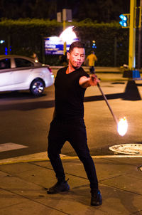 Full length of man performing with fire on street at night