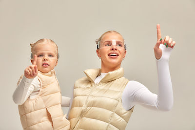 Portrait of smiling young woman gesturing while standing against white background