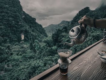 Person holding umbrella on mountain against sky