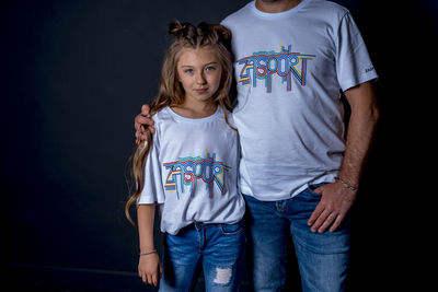 Full length of siblings standing against black background