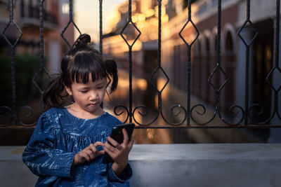 Girl looking away while standing on mobile phone