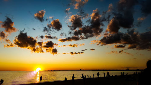 Silhouette people against sea during sunset