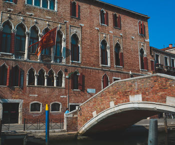 Low angle view of arch bridge over canal against buildings