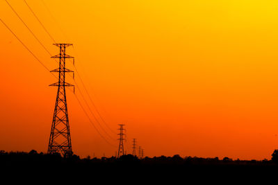 Silhouette electricity pylon against romantic sky at sunset