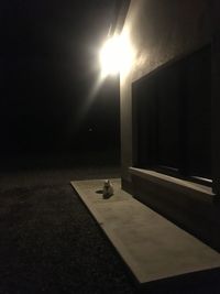 Illuminated lamp on table against wall