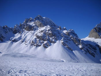 Scenic view of snowcapped mountains against clear blue sky