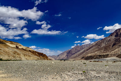 Scenic view of road and mountains against blue sky