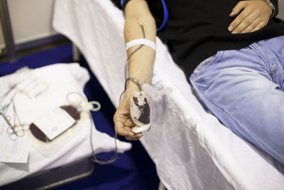 Midsection of man donating blood while lying in hospital