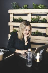 Young woman using mobile phone while sitting on table