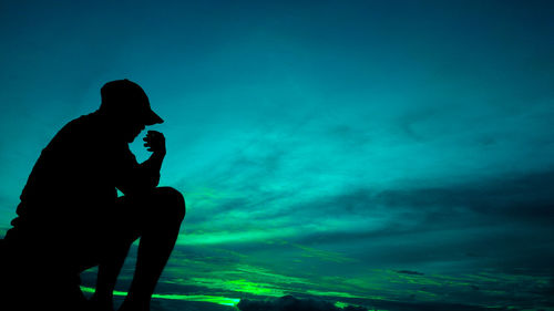 Silhouette man photographing sea against blue sky