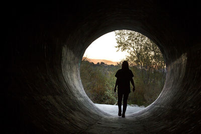 Rear view of silhouette man walking in tunnel