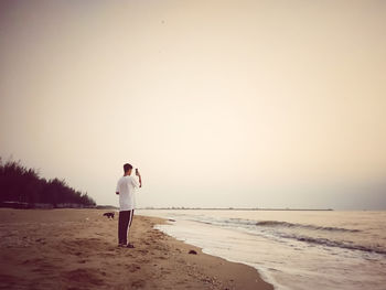 Man standing on beach against clear sky