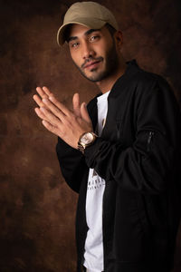 Portrait of young man standing against black background