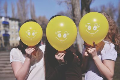 Friends covering face with balloons