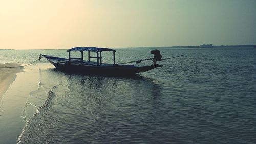 Silhouette boat in sea against clear sky during sunset