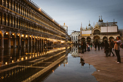 People at illuminated city against sky