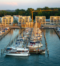 Sailboats moored in canal by city buildings against sky