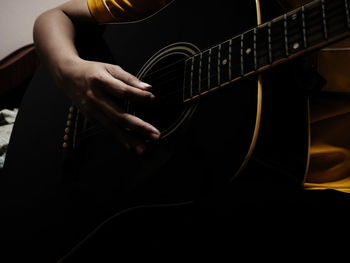 Midsection of man playing guitar