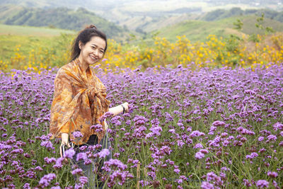 Woman standing on purple flowering plants on field