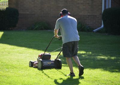 Rear view of man mowing the grass