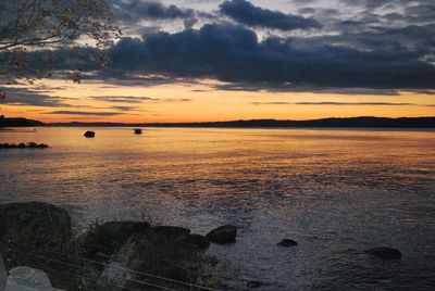 Scenic view of lake against cloudy sky at sunset