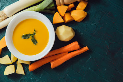 Freshly made pumpkin purée with its ingredients on a green background