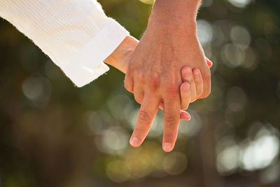 Cropped image of man and woman holding hands