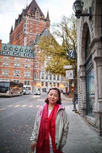 Portrait of smiling young woman standing on street in city