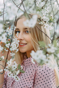 Blonde girl on a spring walk in the garden with cherry blossoms. female portrait, close-up.