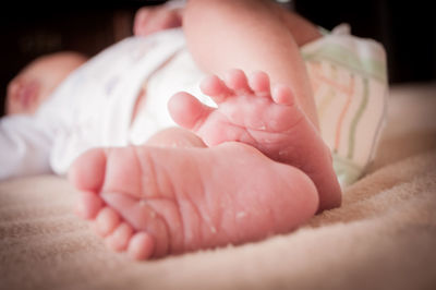 Close-up of newborn baby lying on bed