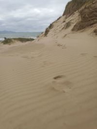 Surface level of sand dunes at beach against sky