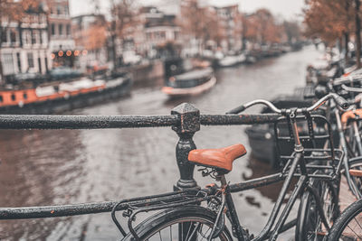 Close-up of bicycle by canal and buildings