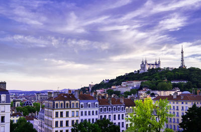 Buildings in city against cloudy sky