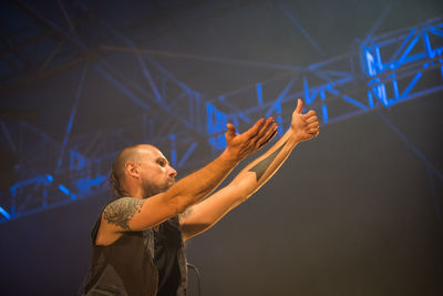 Man with arms raised standing at music concert