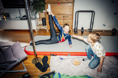 Girl practicing while brother feeding sister in living room