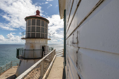 Lighthouse by sea against sky