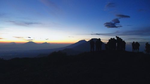 Silhouette people on mountain against sky during sunset