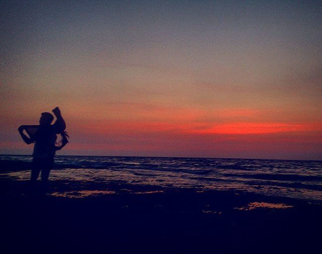 sea, horizon over water, sunset, water, beach, silhouette, sky, leisure activity, lifestyles, orange color, shore, scenics, beauty in nature, standing, tranquil scene, tranquility, full length, nature