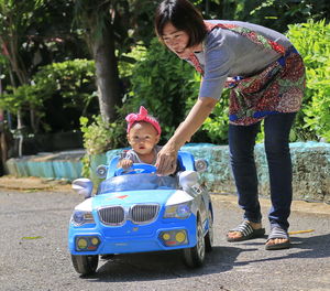 Mother with baby daughter driving toy car