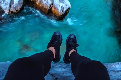 Low section of person on rock by swimming pool