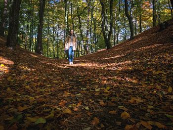 Full length of woman standing on tree trunk in forest