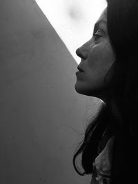 Close-up portrait of young woman looking away against wall