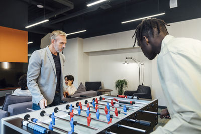 Businessmen playing foosball in office