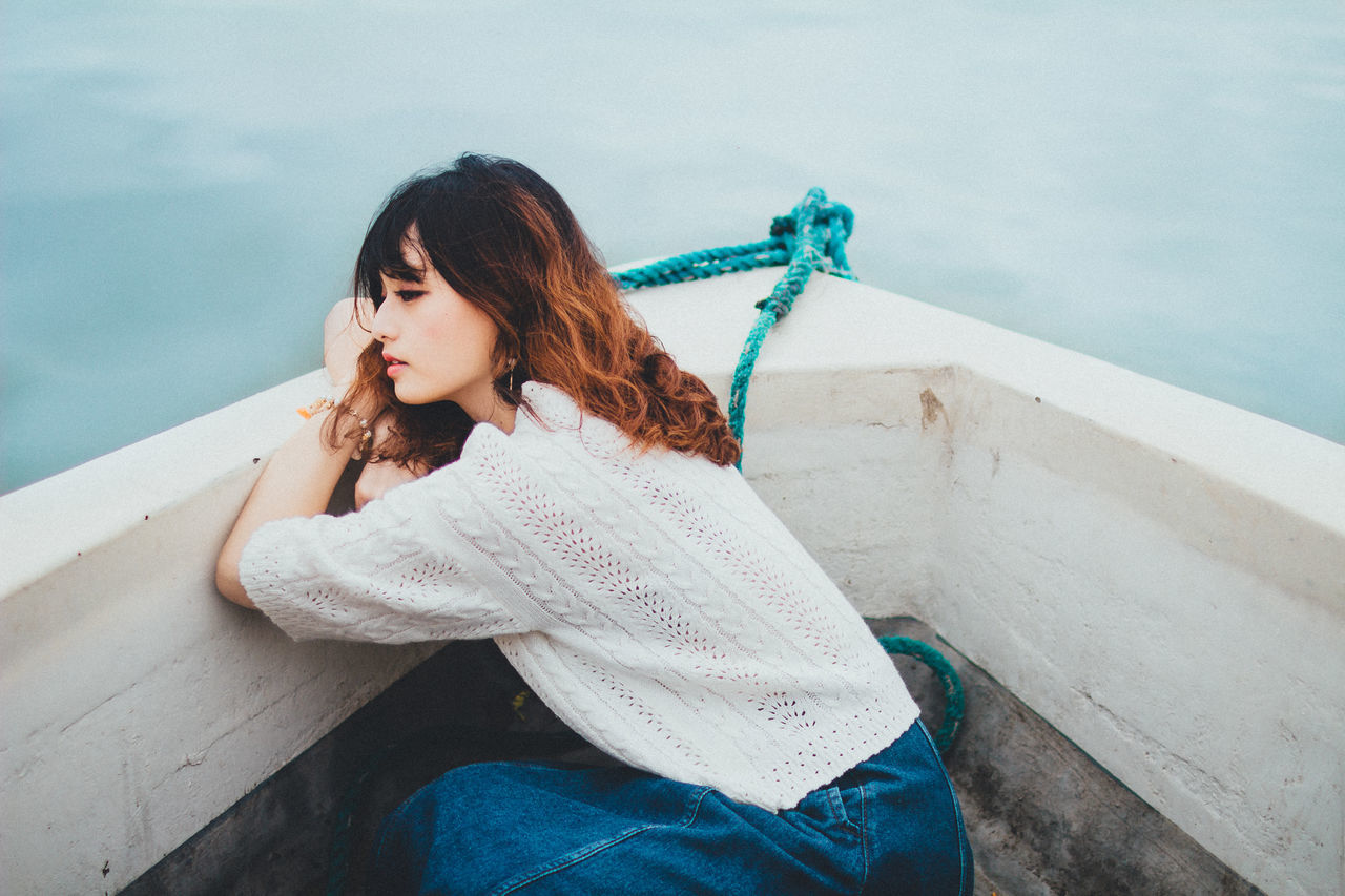 BEAUTIFUL YOUNG WOMAN SITTING ON WATER