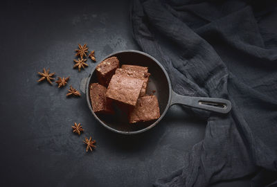 Pieces of baked brownie in a metal black frying pan on the table, top view